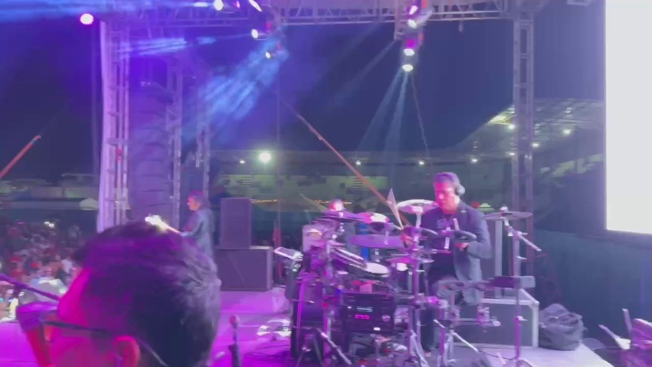 Baterista en vivo sobre el escenario con el estadio de fondo