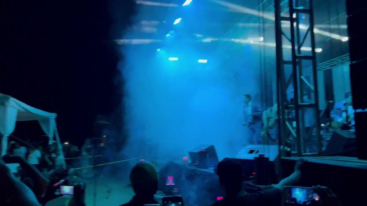 Público frente al escenario entre humo y luces azules